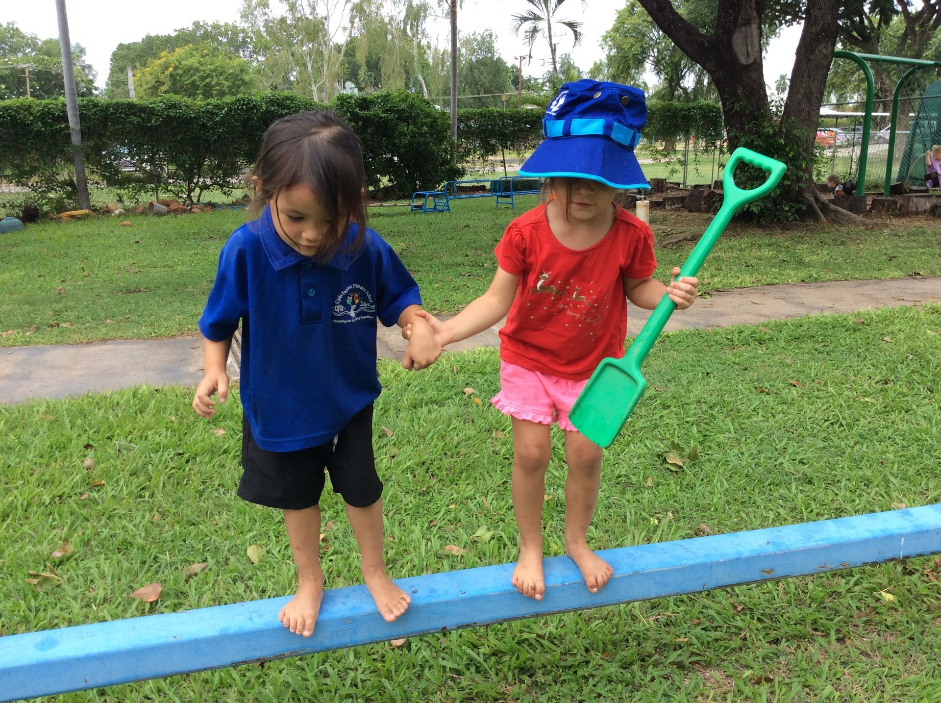 A boy and a girl are holding hands while walking on a balance beam