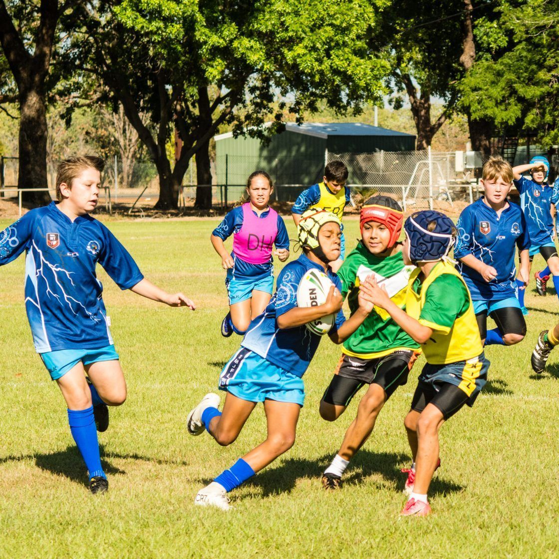 A group of children are playing rugby on a field