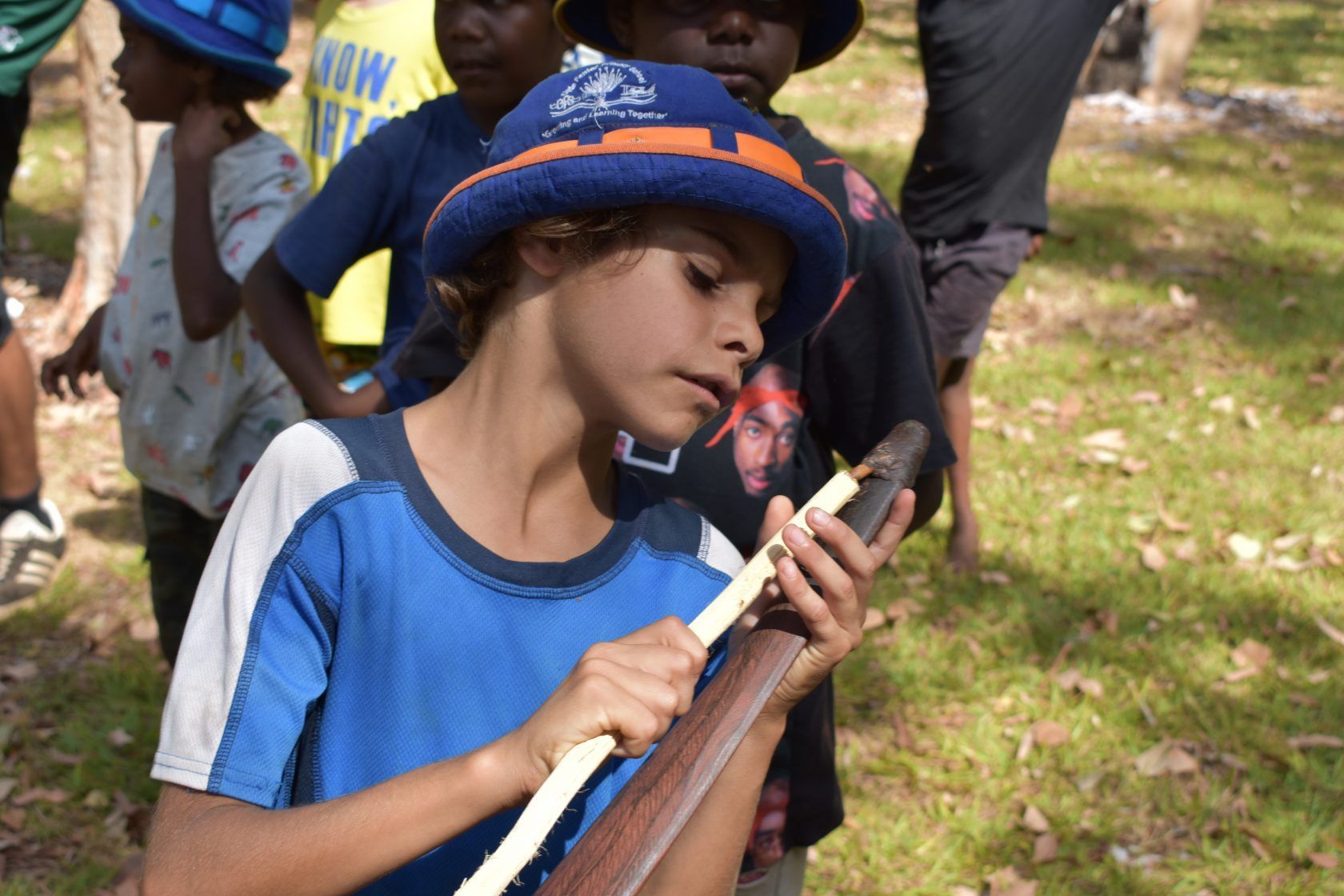 A young boy in a blue shirt is playing a flute