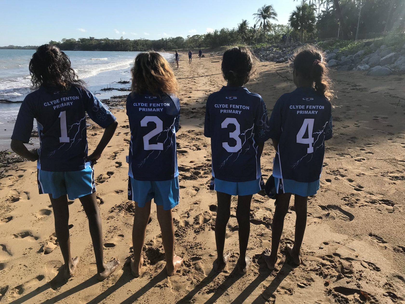 A group of girls standing on a beach with numbers 1 2 3 and 4 on their backs