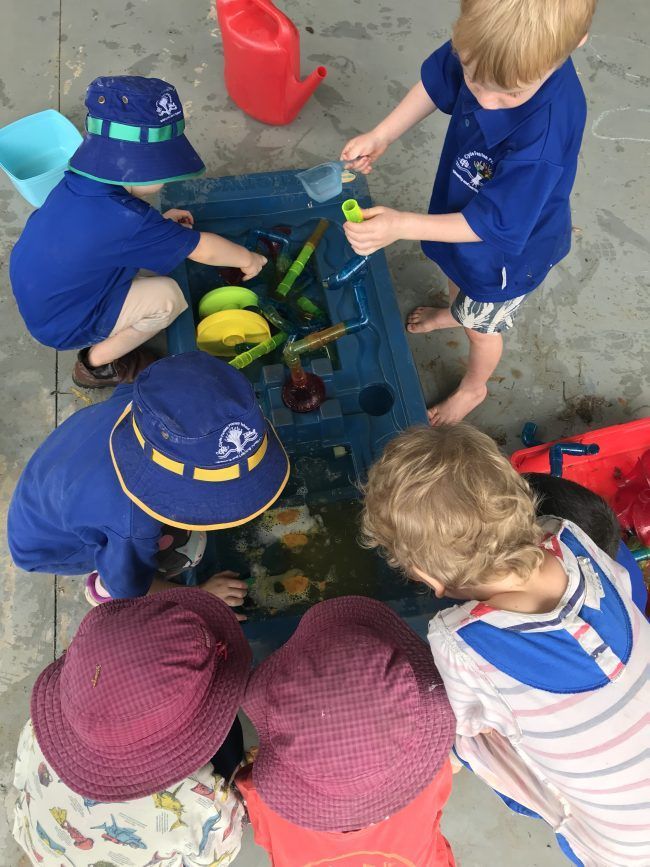 A group of children are playing in a water table.