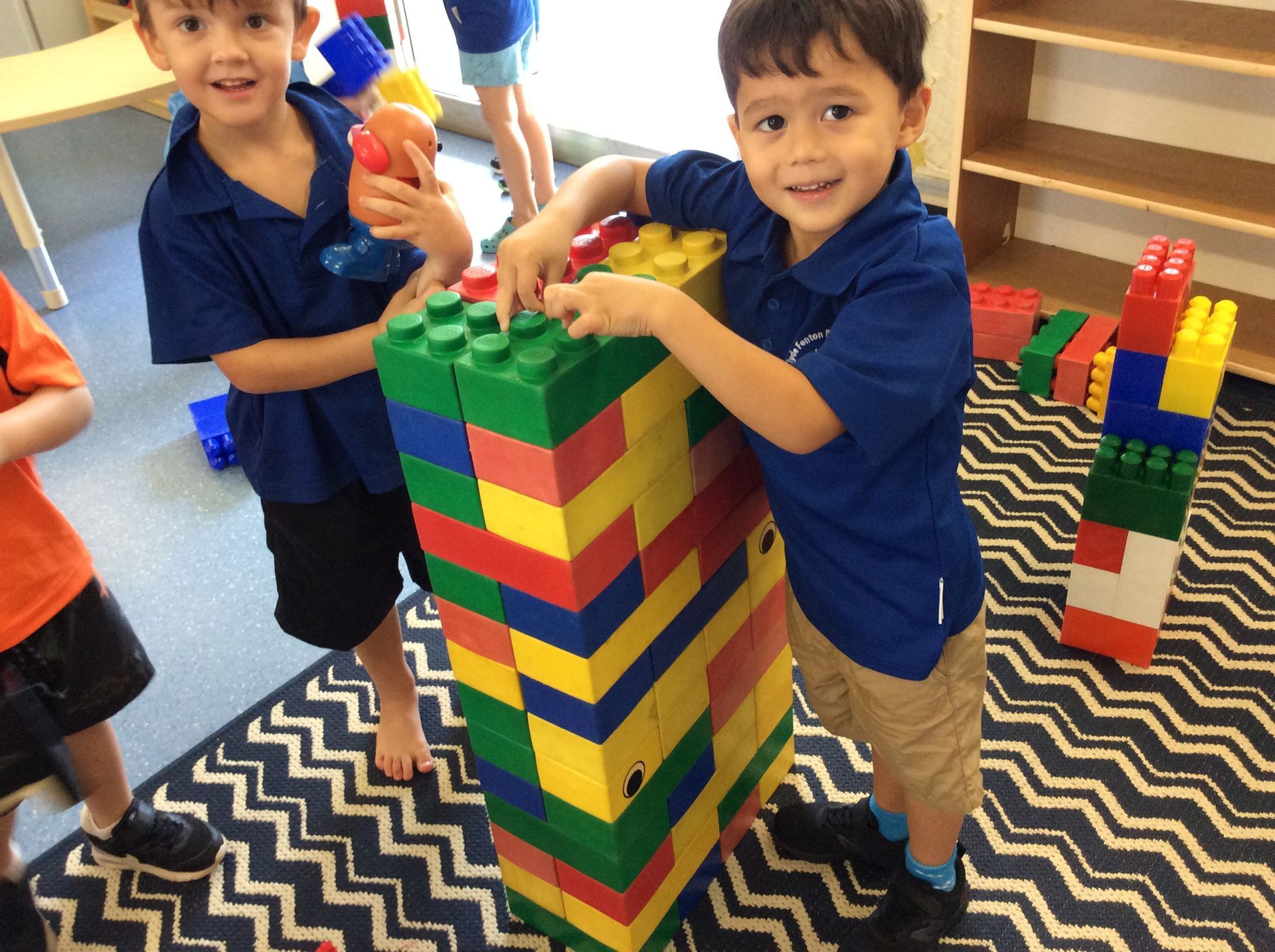 Two young boys are playing with a large stack of lego blocks.