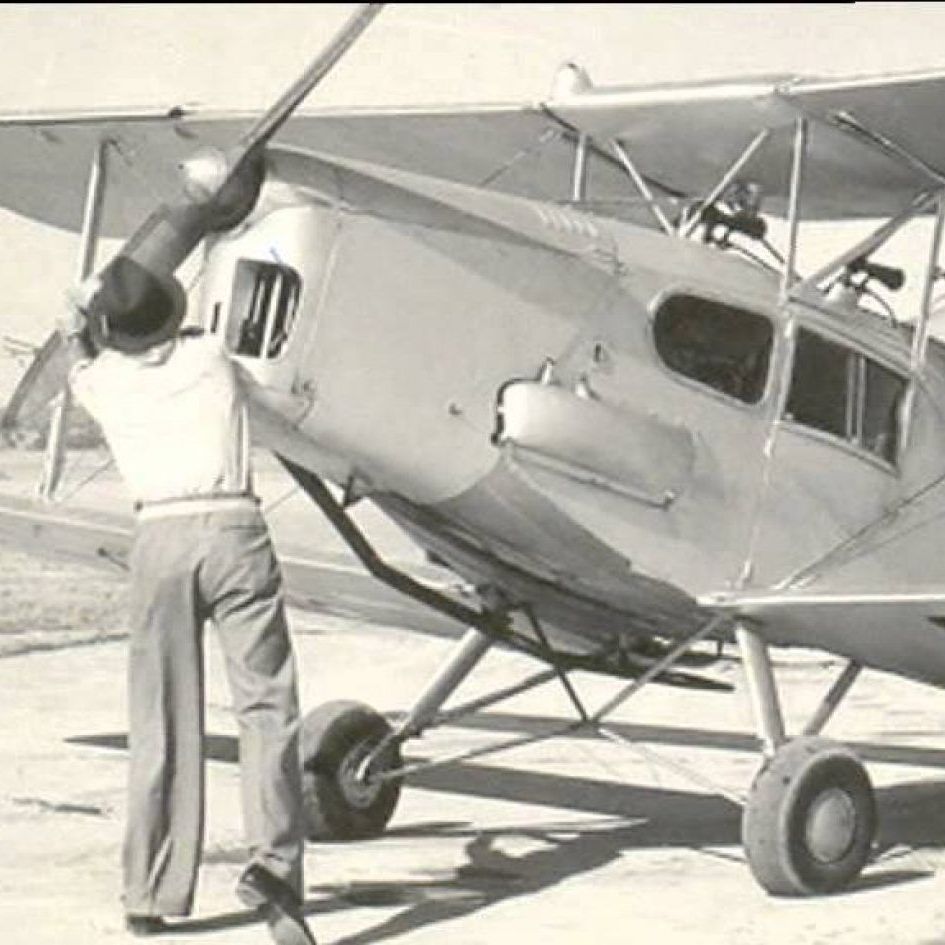 A black and white photo of a man standing next to an airplane