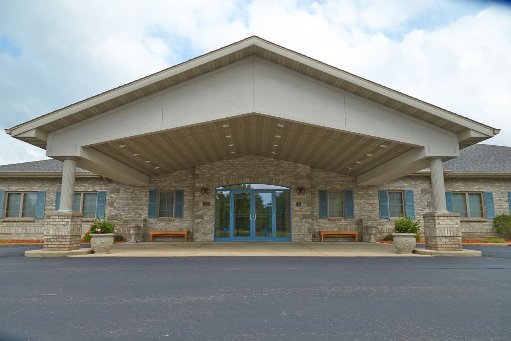 Front view of a stone building with a large peaked roof and glass entrance
