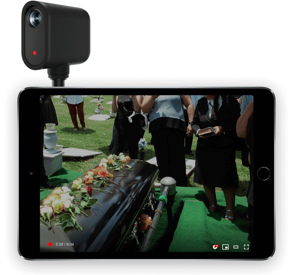 Small black camera mounted above a tablet showing a funeral scene outdoors