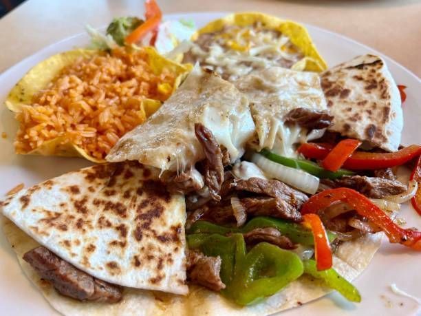 A plate of Mexican food: quesadilla, fajitas, rice, and a taco.