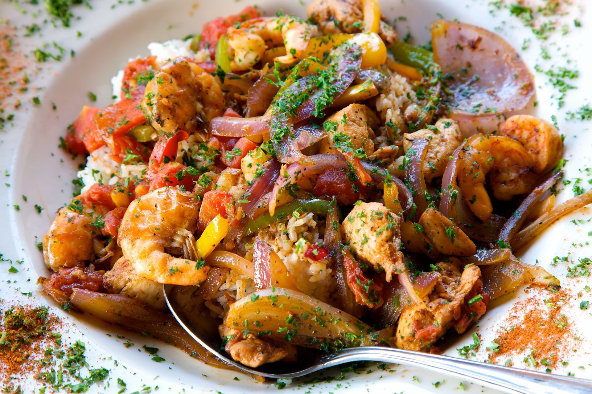 Bowl of jambalaya with shrimp, chicken, vegetables, and rice, garnished with parsley.