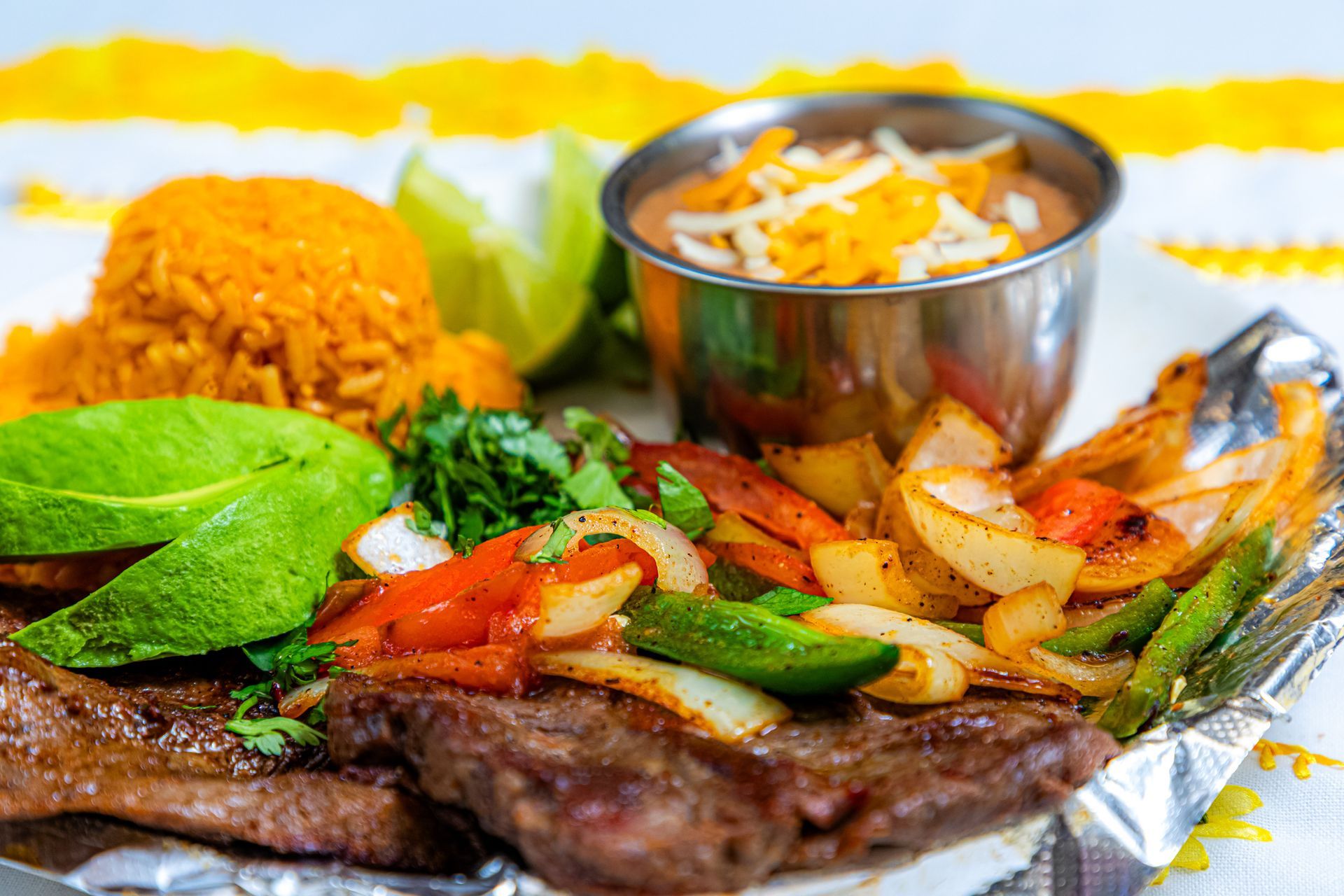 Fajitas with steak, rice, beans, avocado, and vegetables on a plate with lime. Fajitas with steak, rice, beans, avocado, and vegetables on a plate with lime.