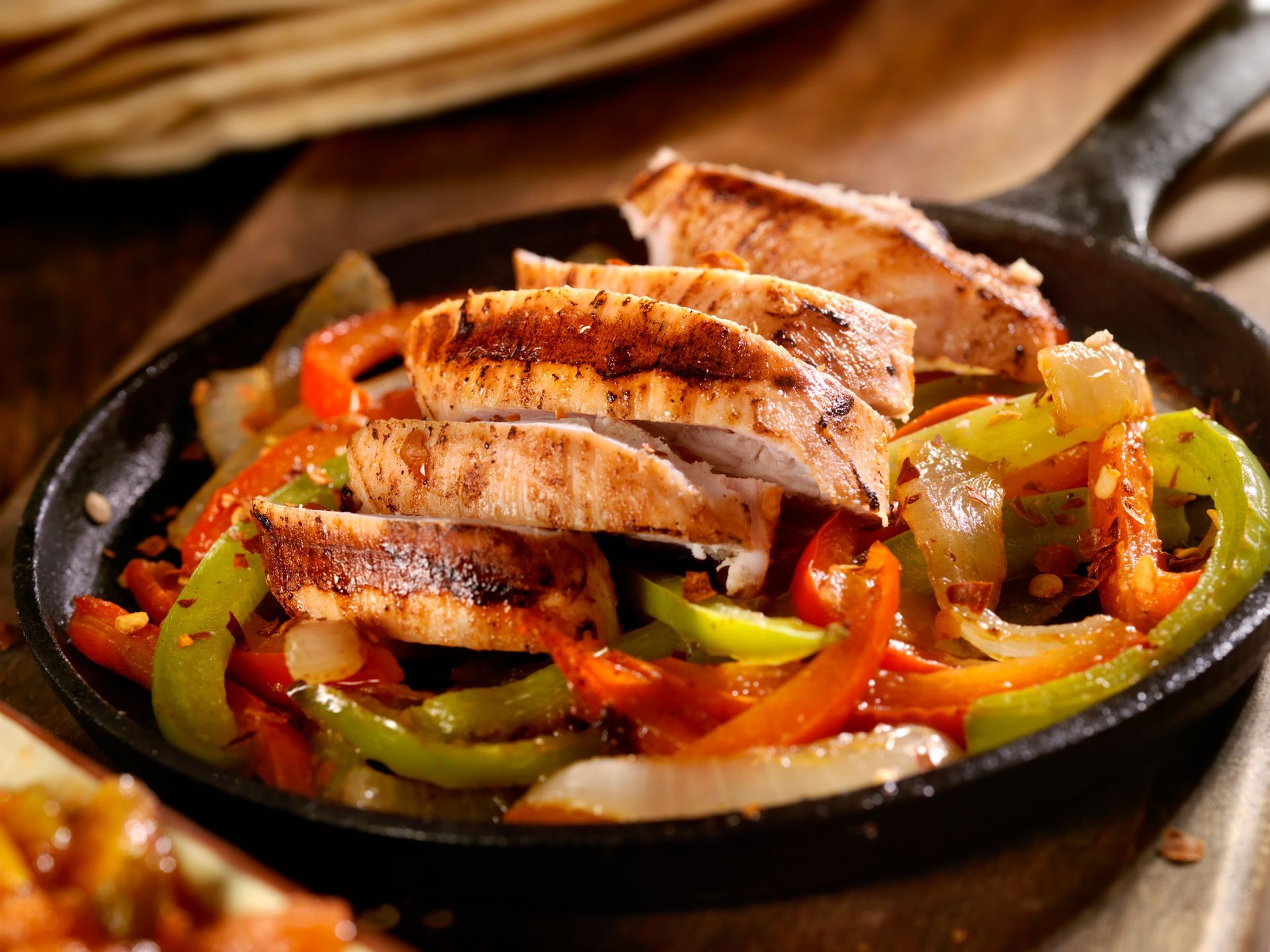 Chicken fajitas in a cast iron skillet with colorful peppers and onions.