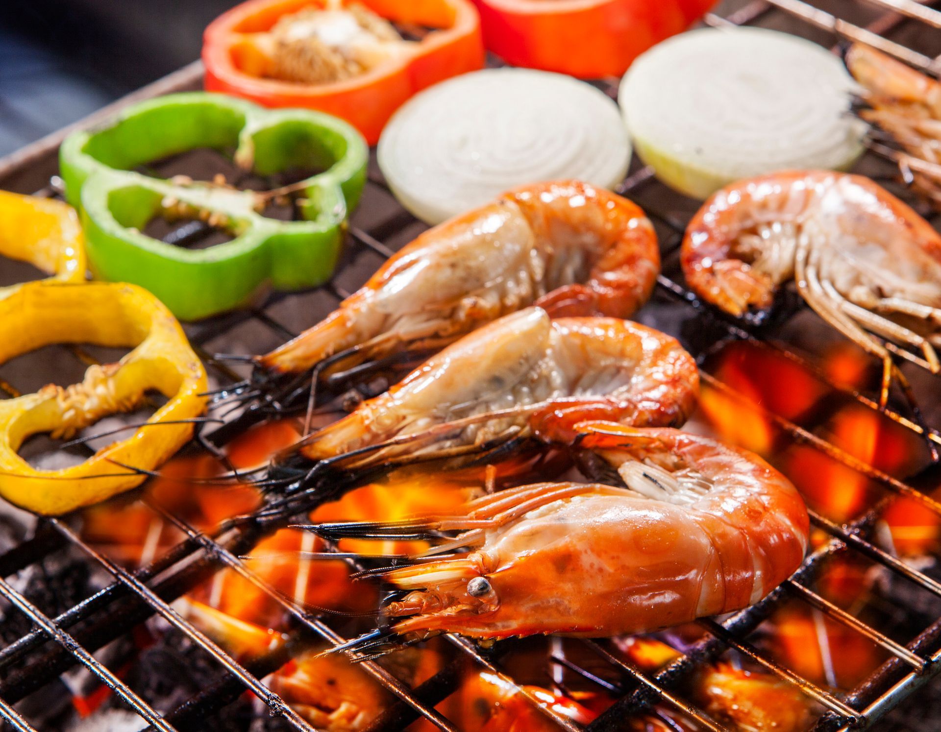 Grilled shrimp, peppers, and onions on a barbecue grill with flames. Grilled shrimp, peppers, and onions on a barbecue grill with flames.
