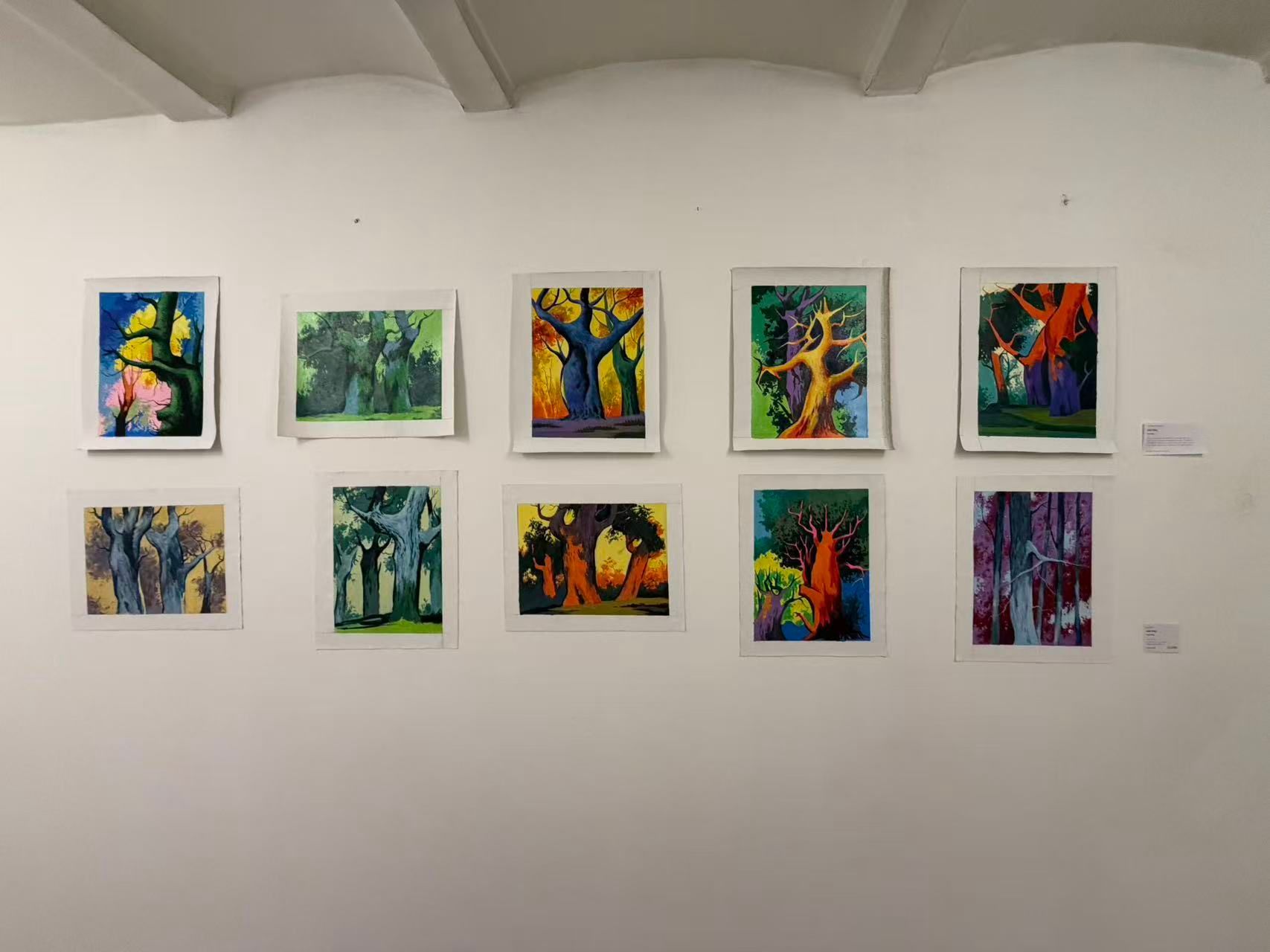 Neun farbenfrohe abstrakte Gemälde, die in zwei Reihen an einer weißen Galeriewand hängen.