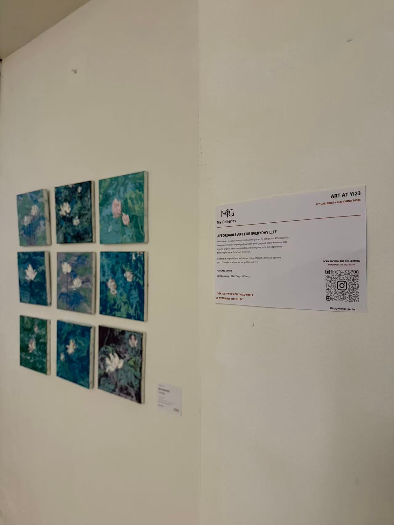 Wanddisplay mit einem 3×3-Raster aus Kunstwerken in Blautönen und einem QR-Code-Schild rechts.