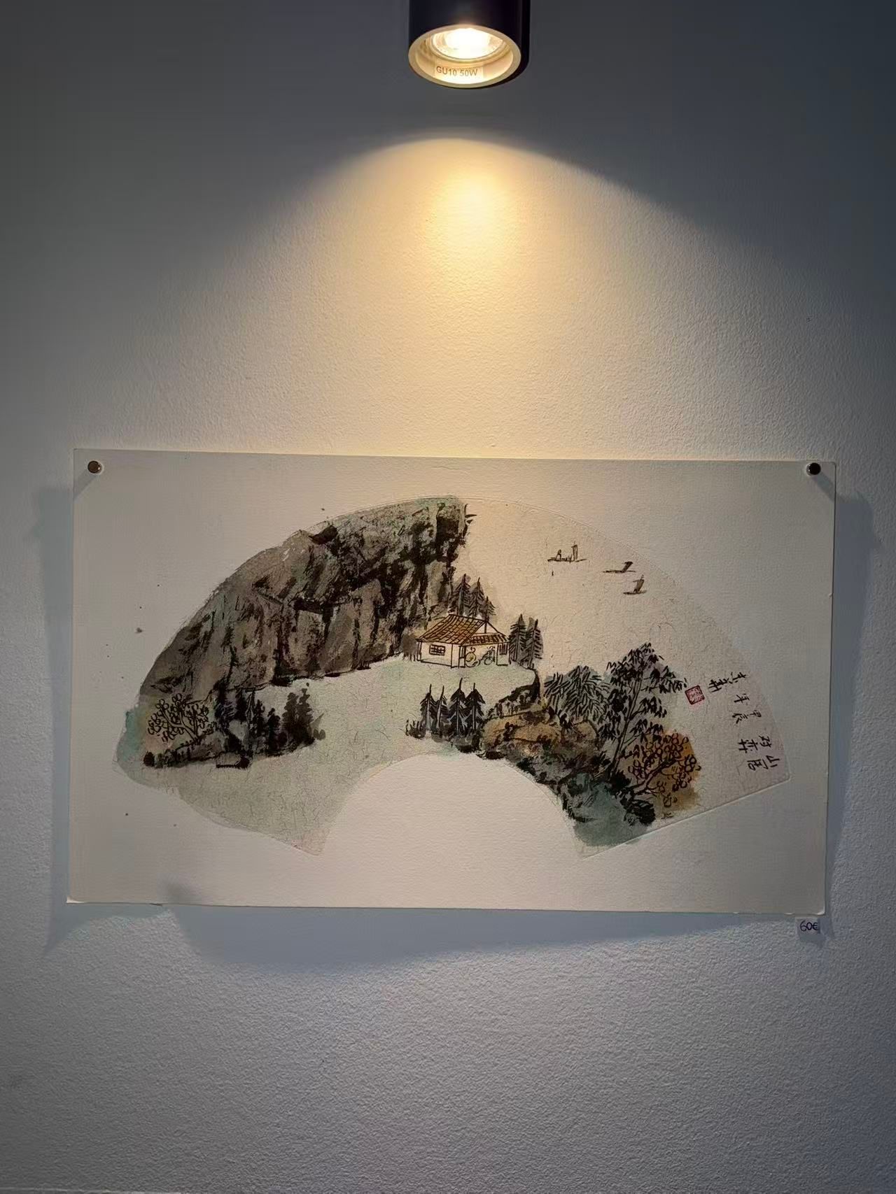 Abstraktes Tuschekunstwerk an einer grauen Wand unter einem Spotlicht montiert