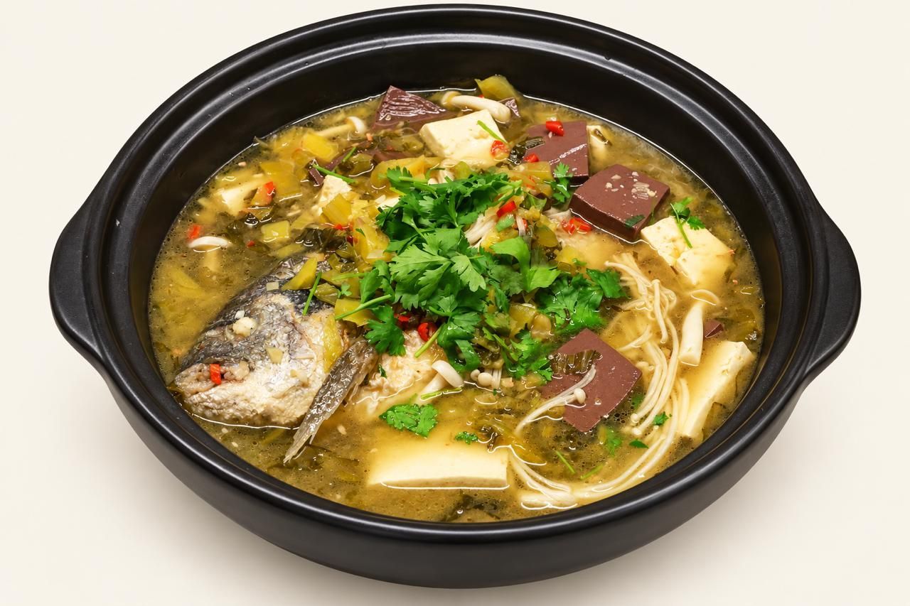 Schwarze Schüssel mit Fischsuppe, Tofu, Pilzen, Kräutern und Nudeln vor hellem Hintergrund