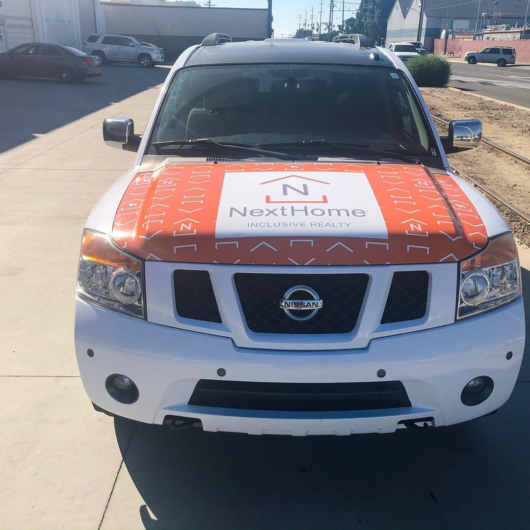 A white suv with an orange and white hood that says next home