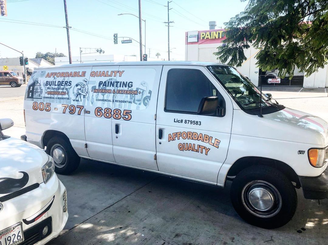 A white van is parked in a parking lot next to a white car.