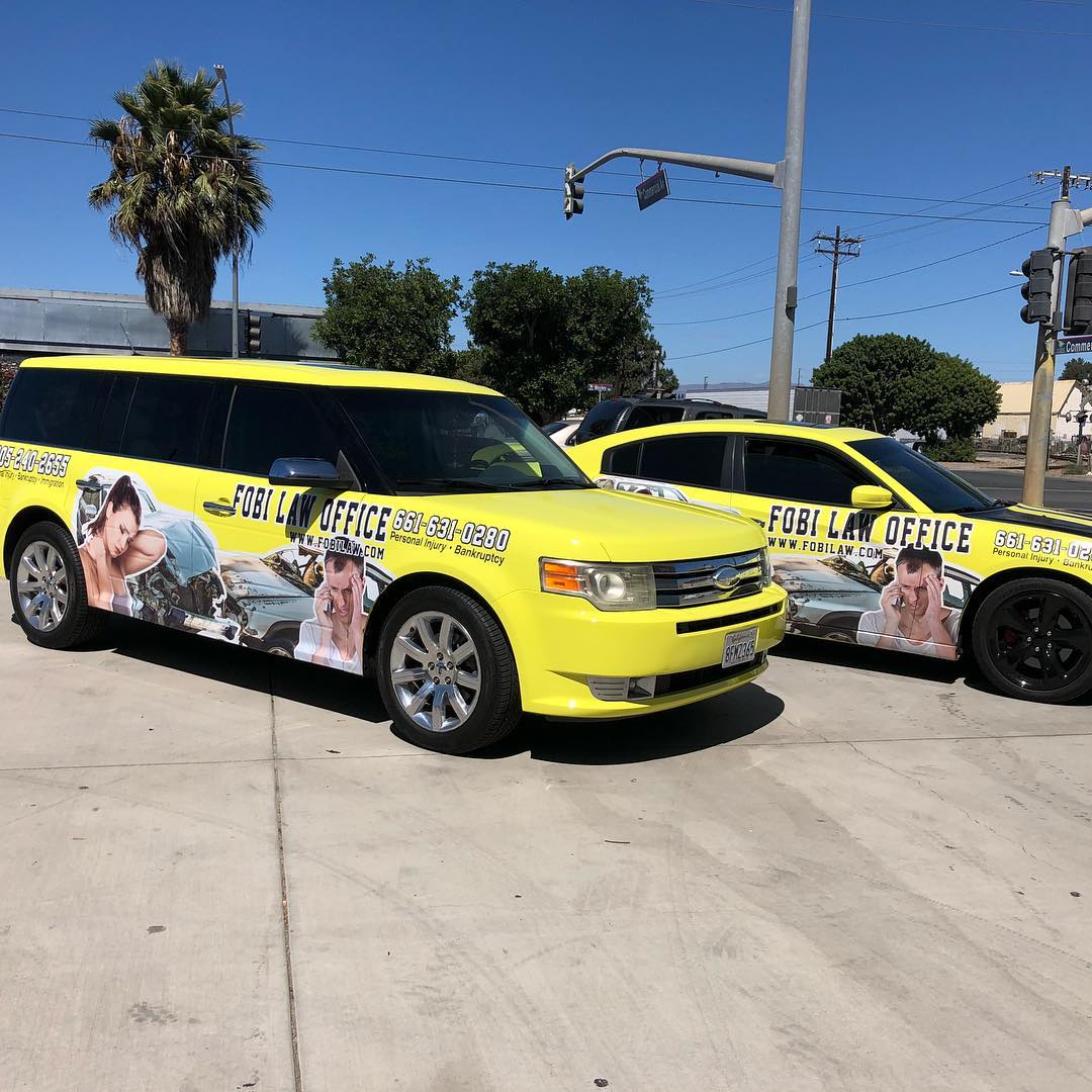 Two yellow police cars are parked next to each other in a parking lot.