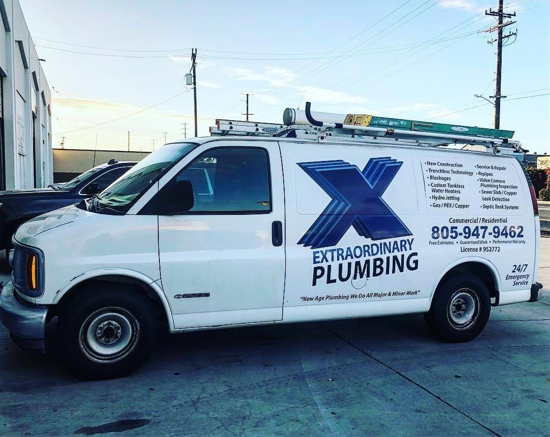 A white van with a blue x on the side is parked in a parking lot.