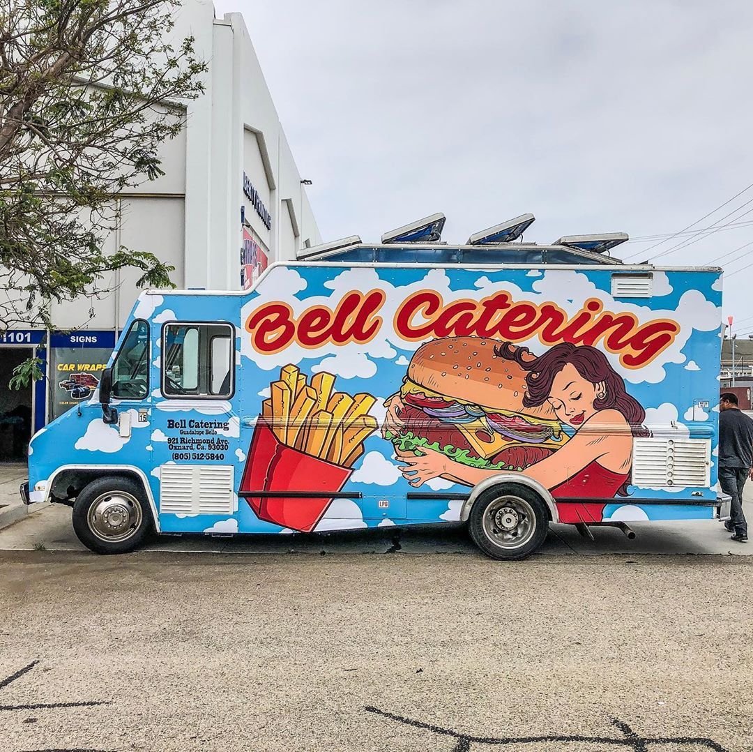 A bell catering food truck is parked in front of a building.