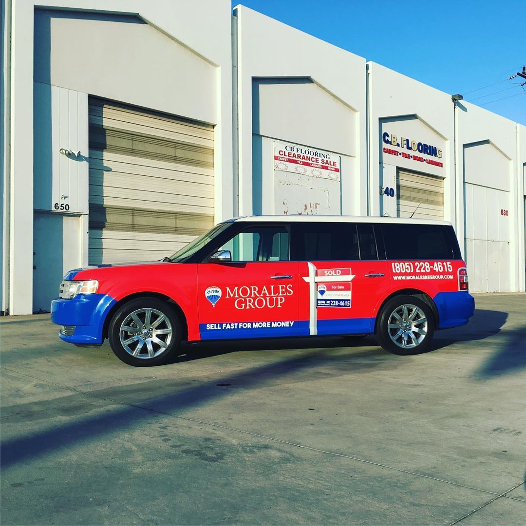 A red and blue morales group van is parked in front of a building