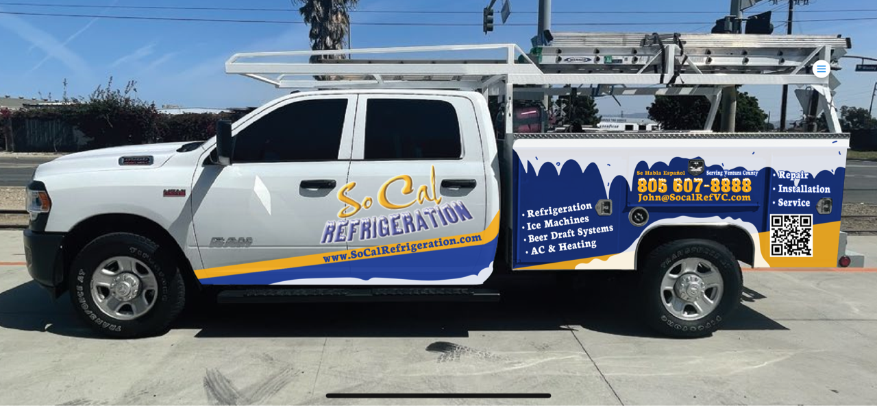 A white and blue truck is parked on the side of the road.