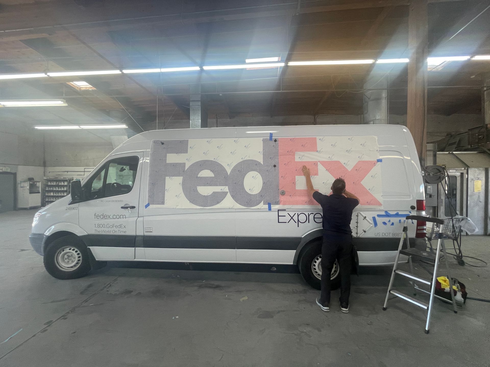 A fedex van is being painted in a garage.