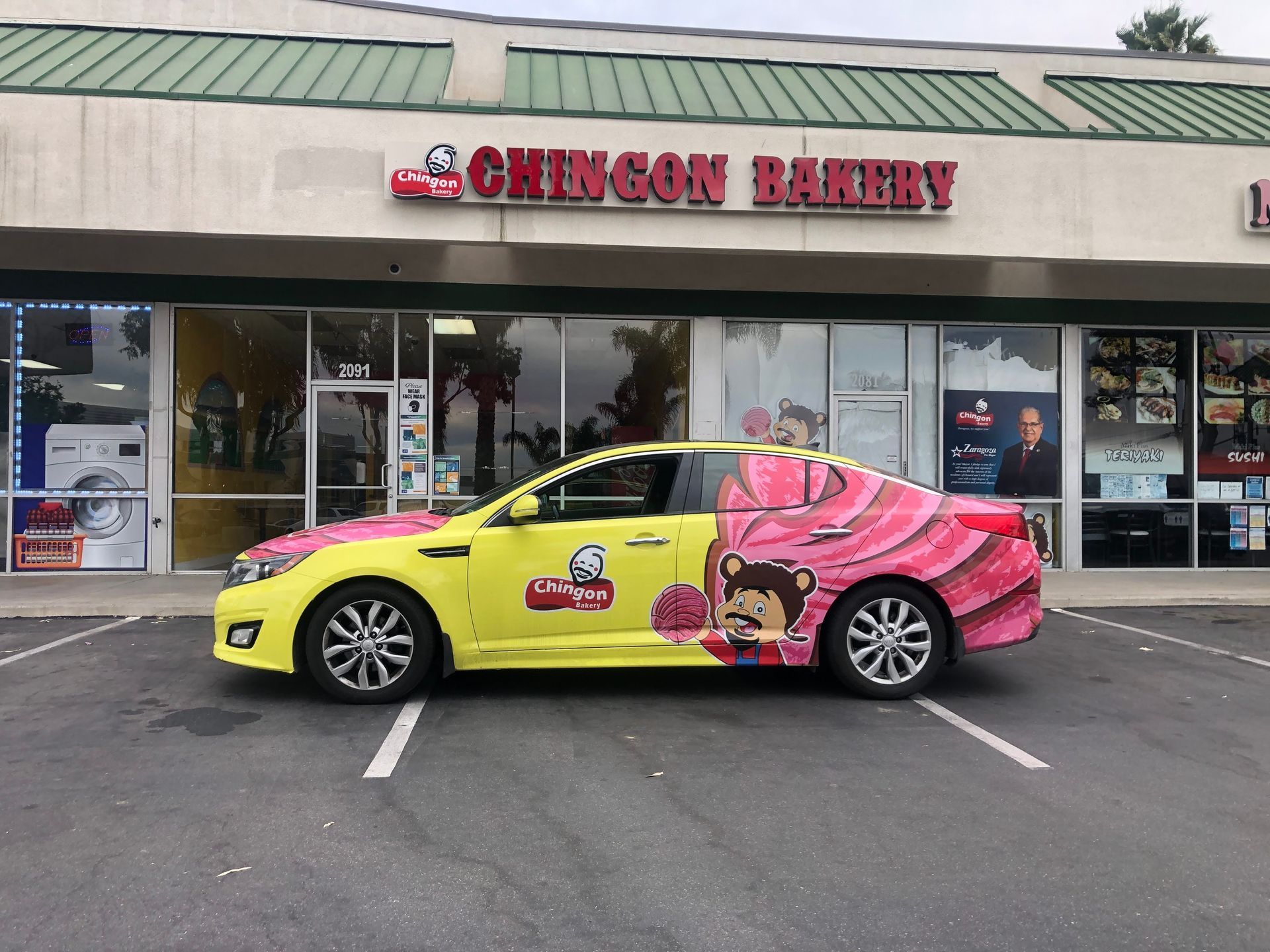 A car is parked in front of a building that says chingon bakery