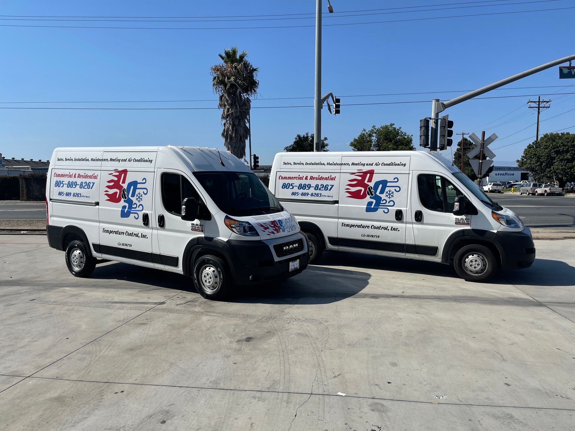 Two white vans are parked next to each other in a parking lot.