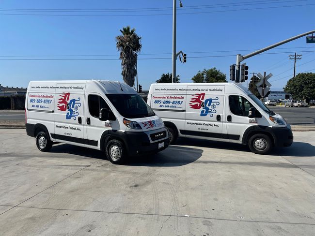 Two white vans are parked next to each other in a parking lot.