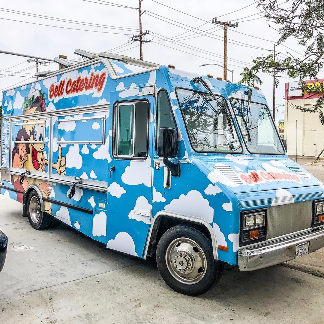A blue and white food truck is parked in a parking lot.