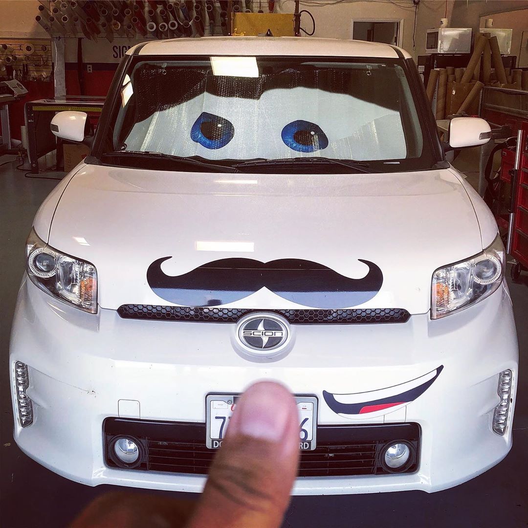A white car with a mustache on it