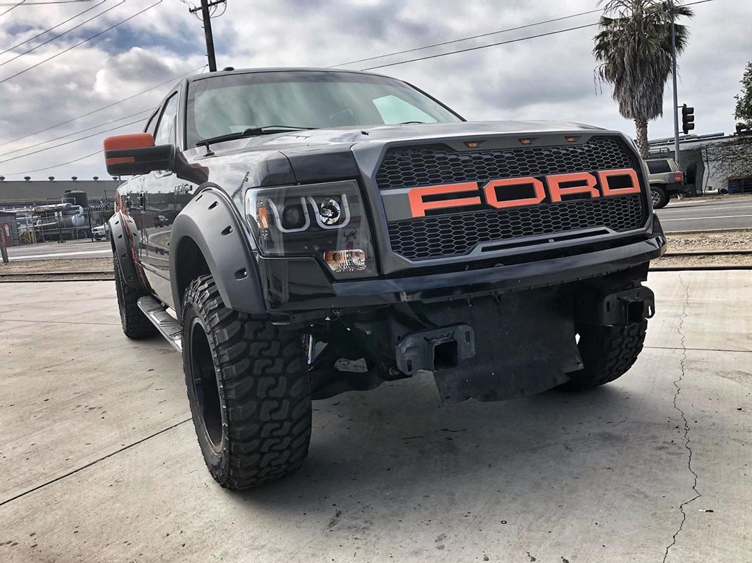 A black ford raptor truck is parked in a parking lot.