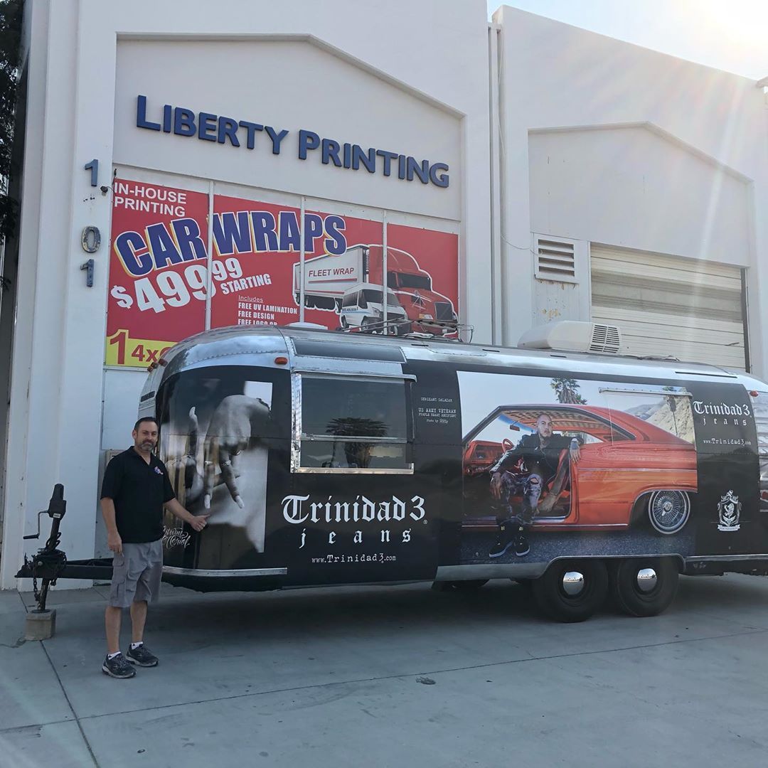 A man is standing next to a car wraps truck in front of liberty printing