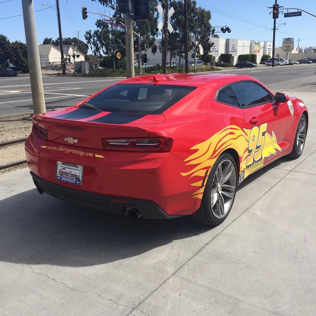 A red car is parked on the side of the road