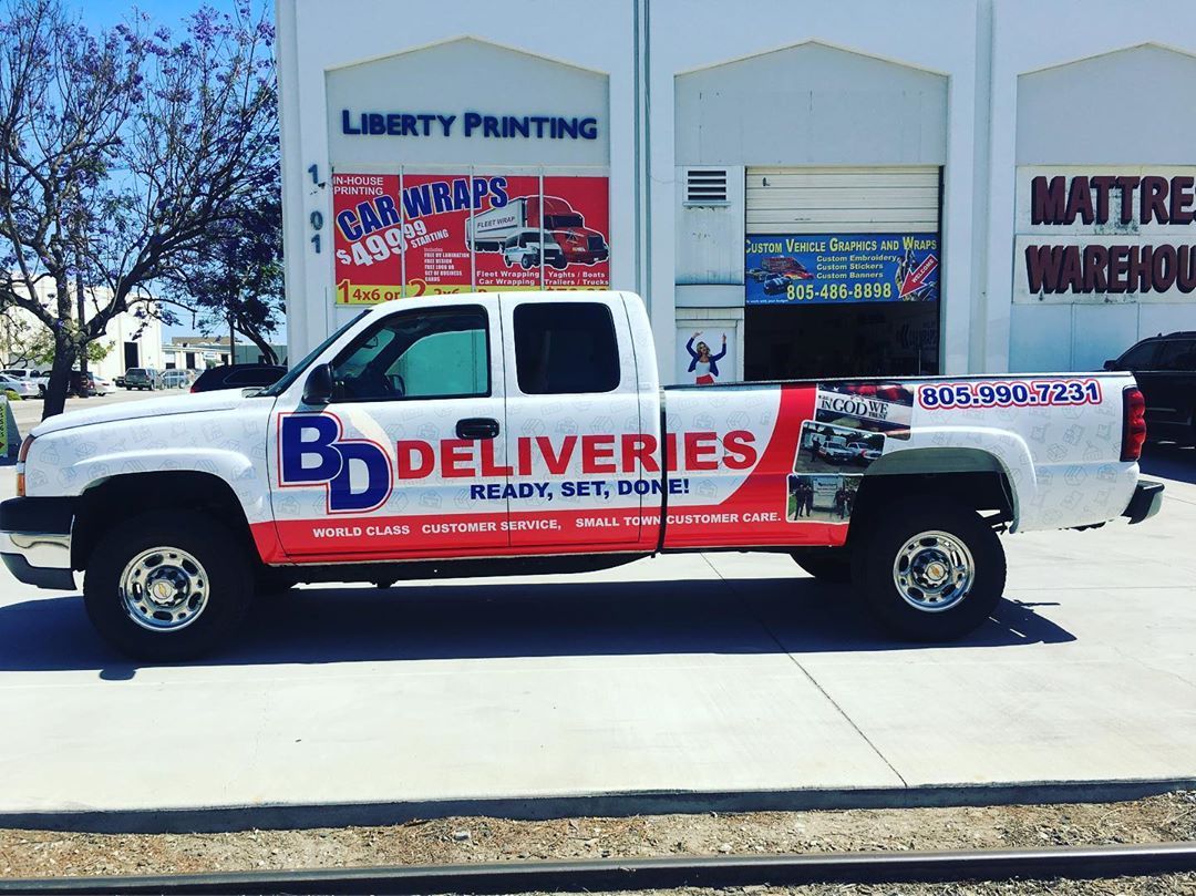 A bd deliveries truck is parked in front of a building.