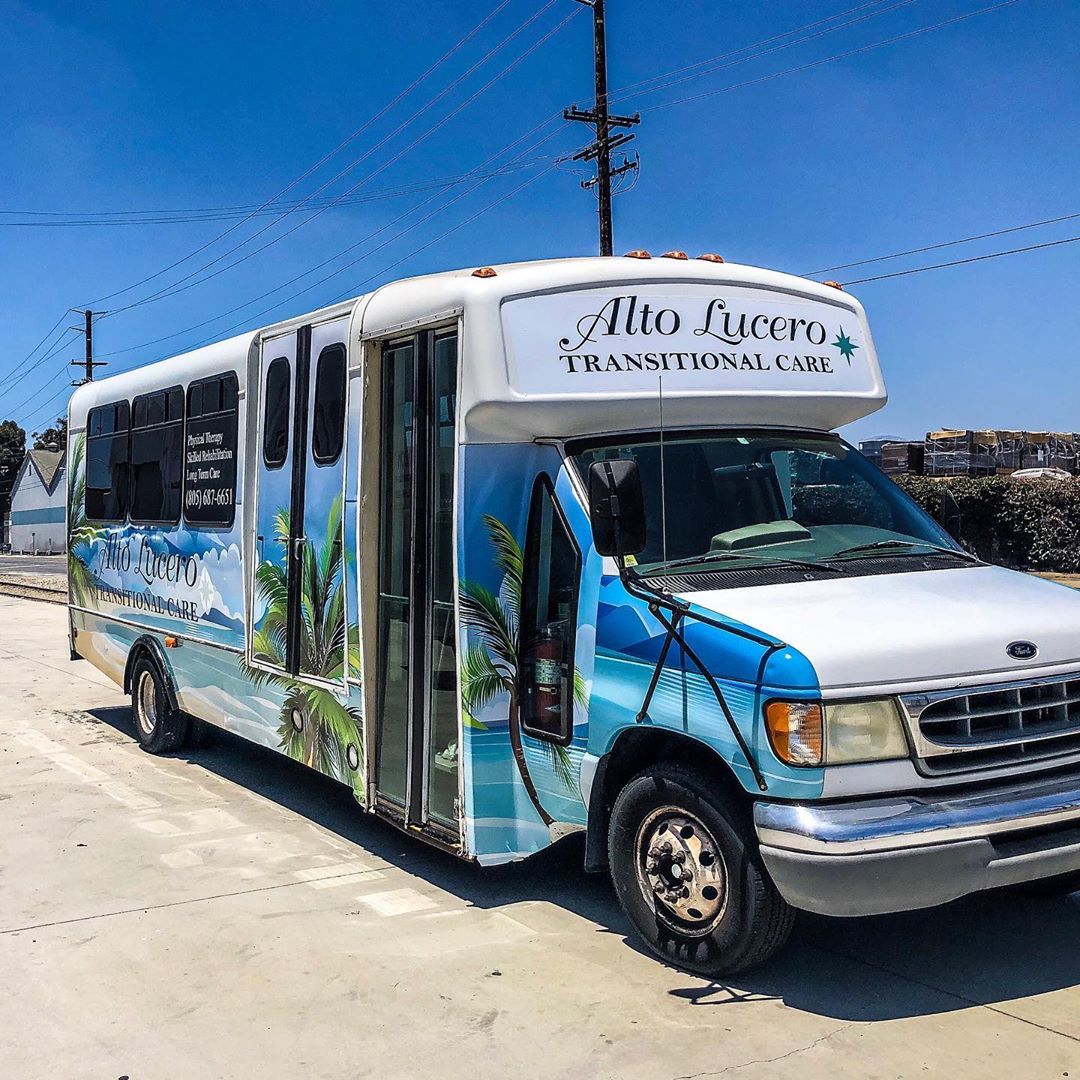 A white and blue bus is parked on the side of the road.