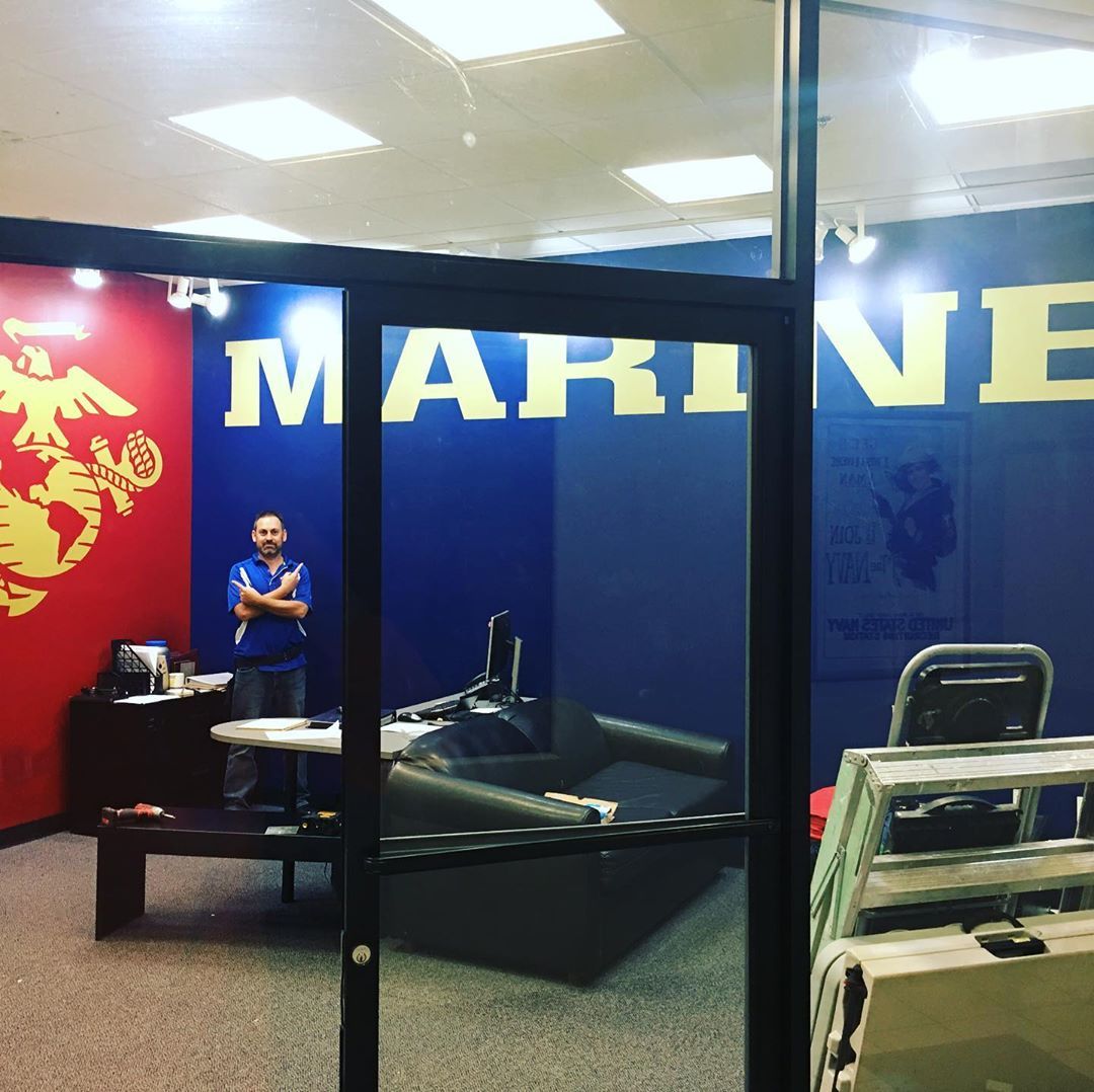 A man stands in a room with the word marine on the wall