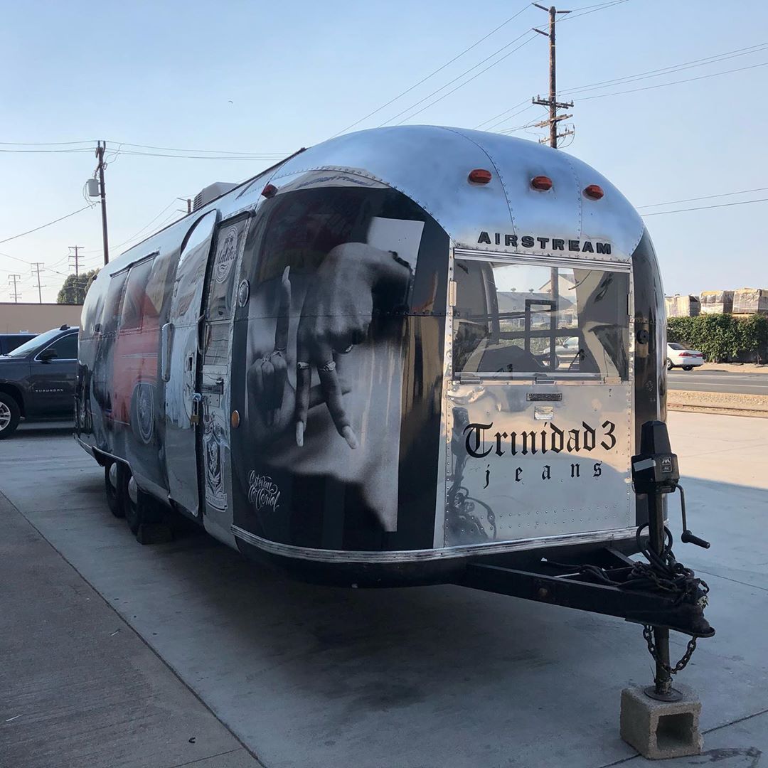 A silver airstream trailer is parked in a parking lot.