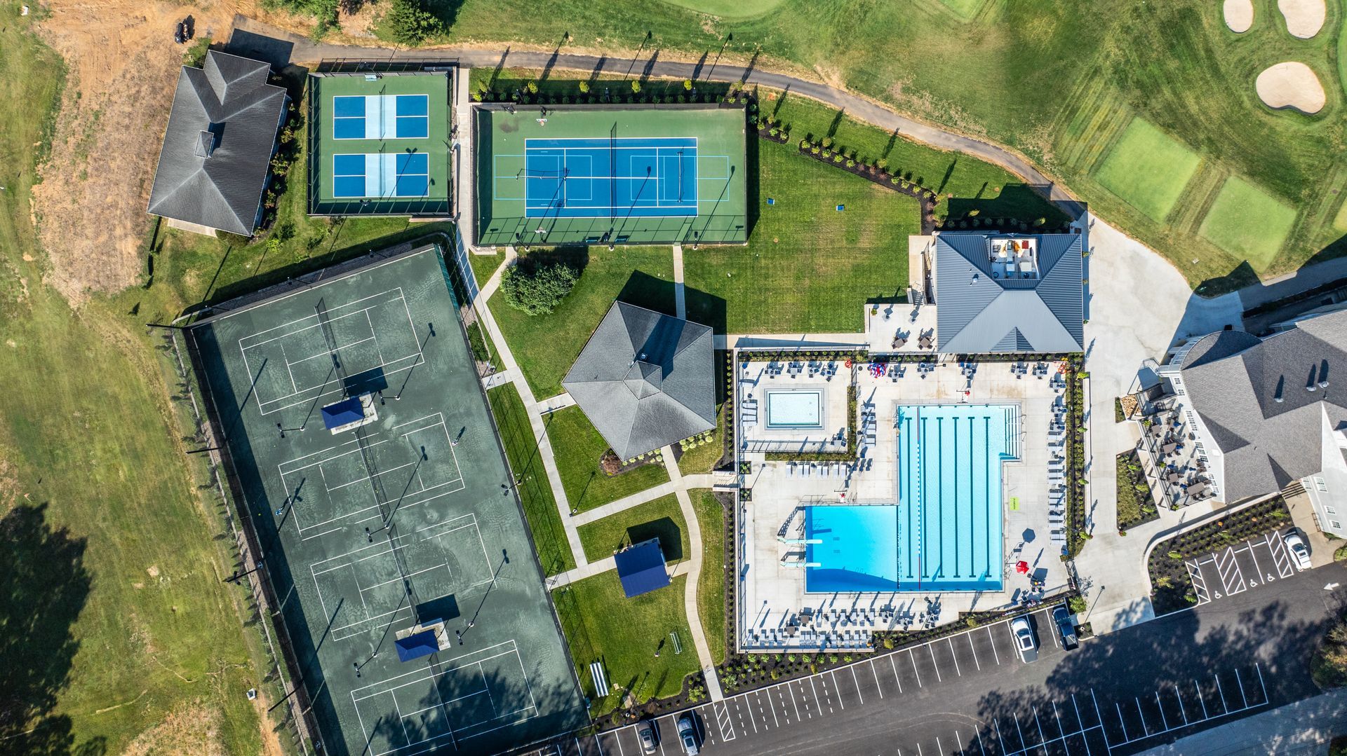 Aerial view of a recreational complex with tennis courts, swimming pool, and golf course.