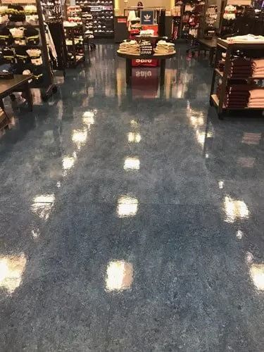 A shiny blue floor in a store aisle, reflecting overhead lights and merchandise displays.