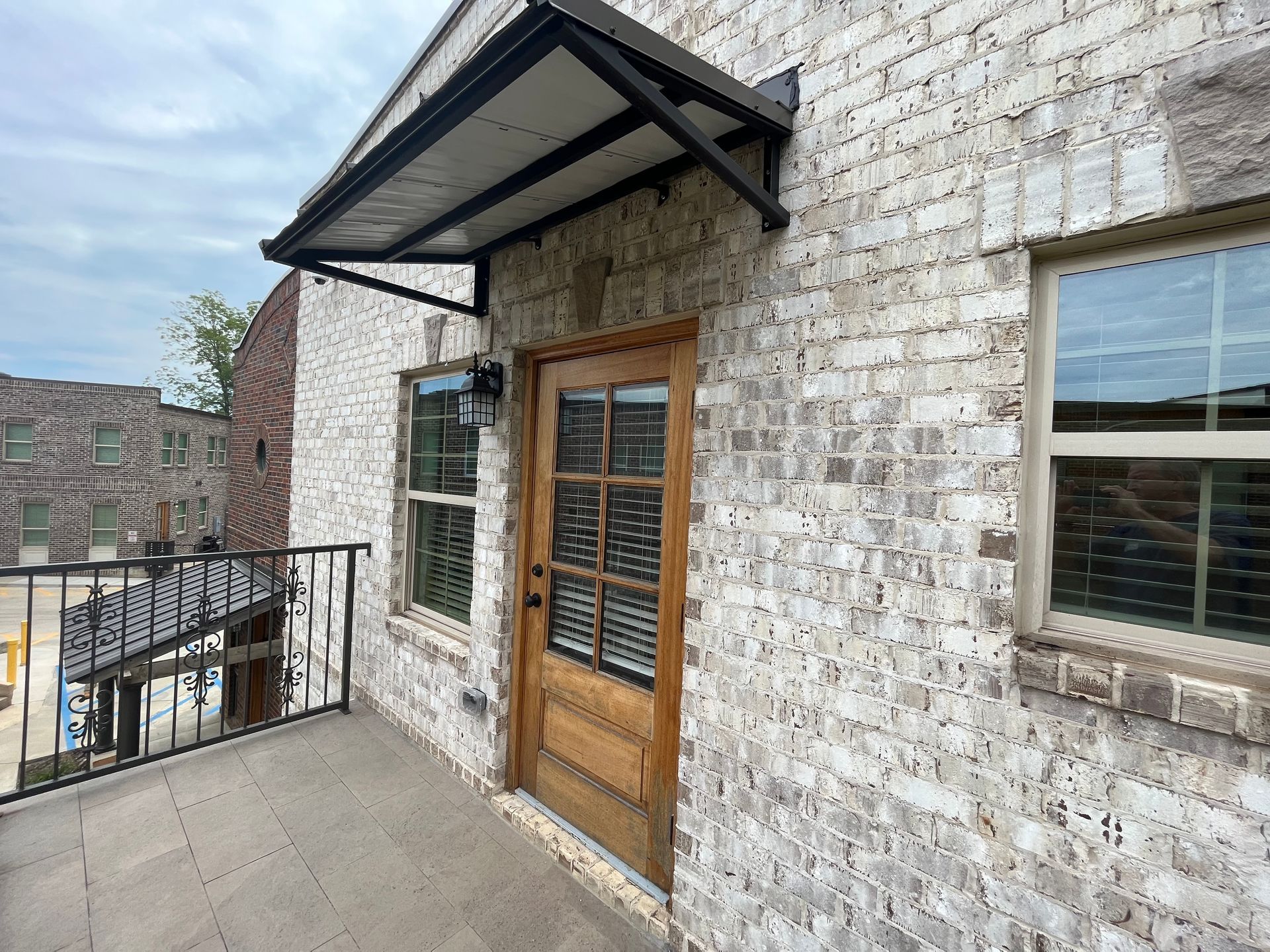 Brick building exterior with door, windows, balcony, and awning.