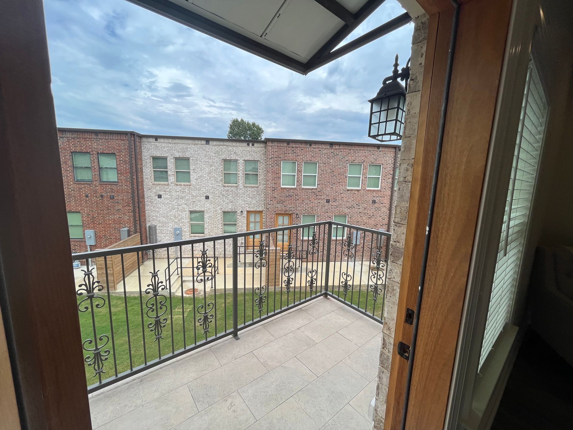Balcony view: Ornate black railing, brick building, cloudy sky.