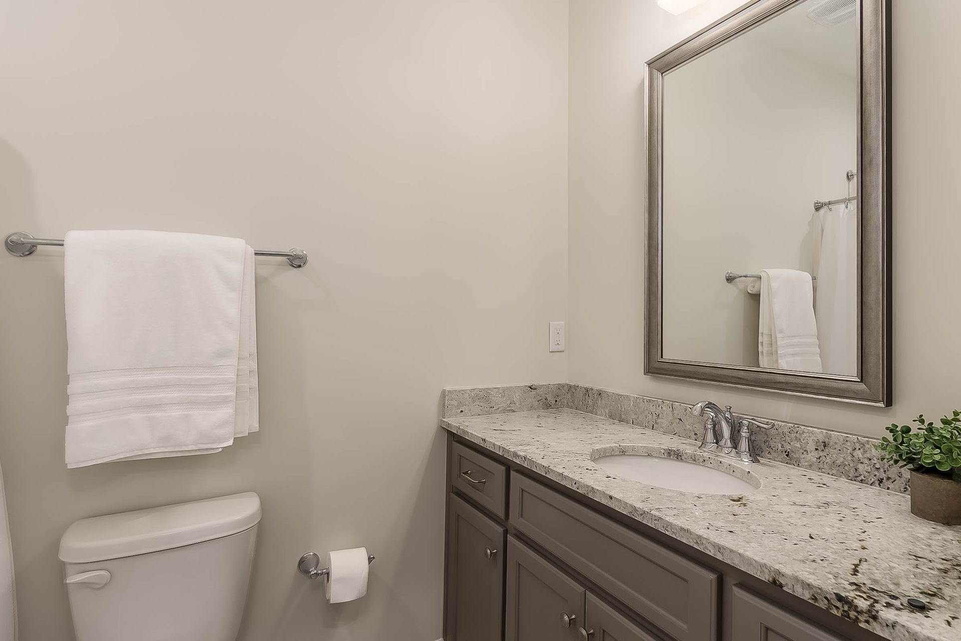 Bathroom with white towel, toilet, gray vanity, and mirror.