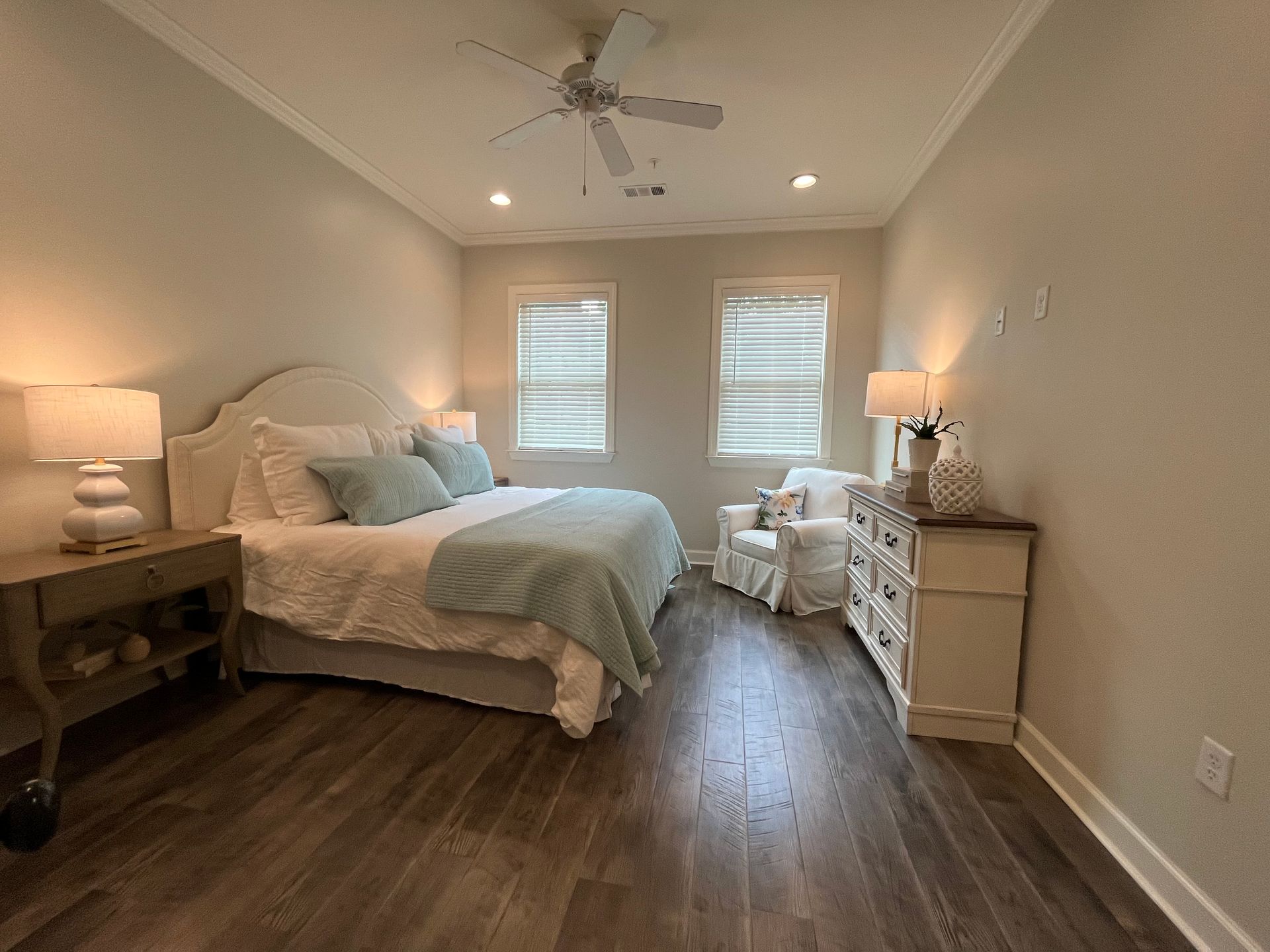 Bedroom with a white bed, light blue accents, white dresser, and armchair.