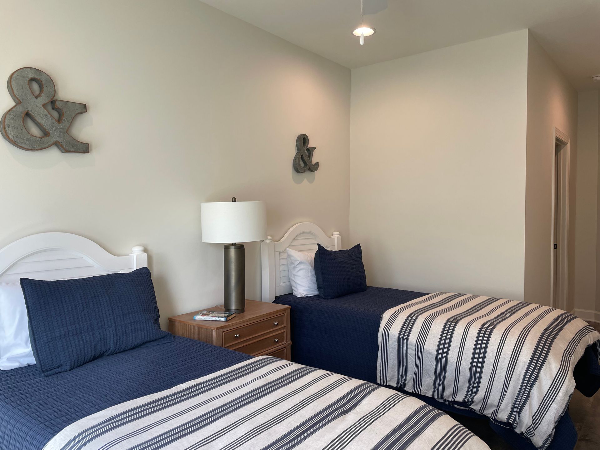Two twin beds with navy bedding and a nightstand in a bedroom.