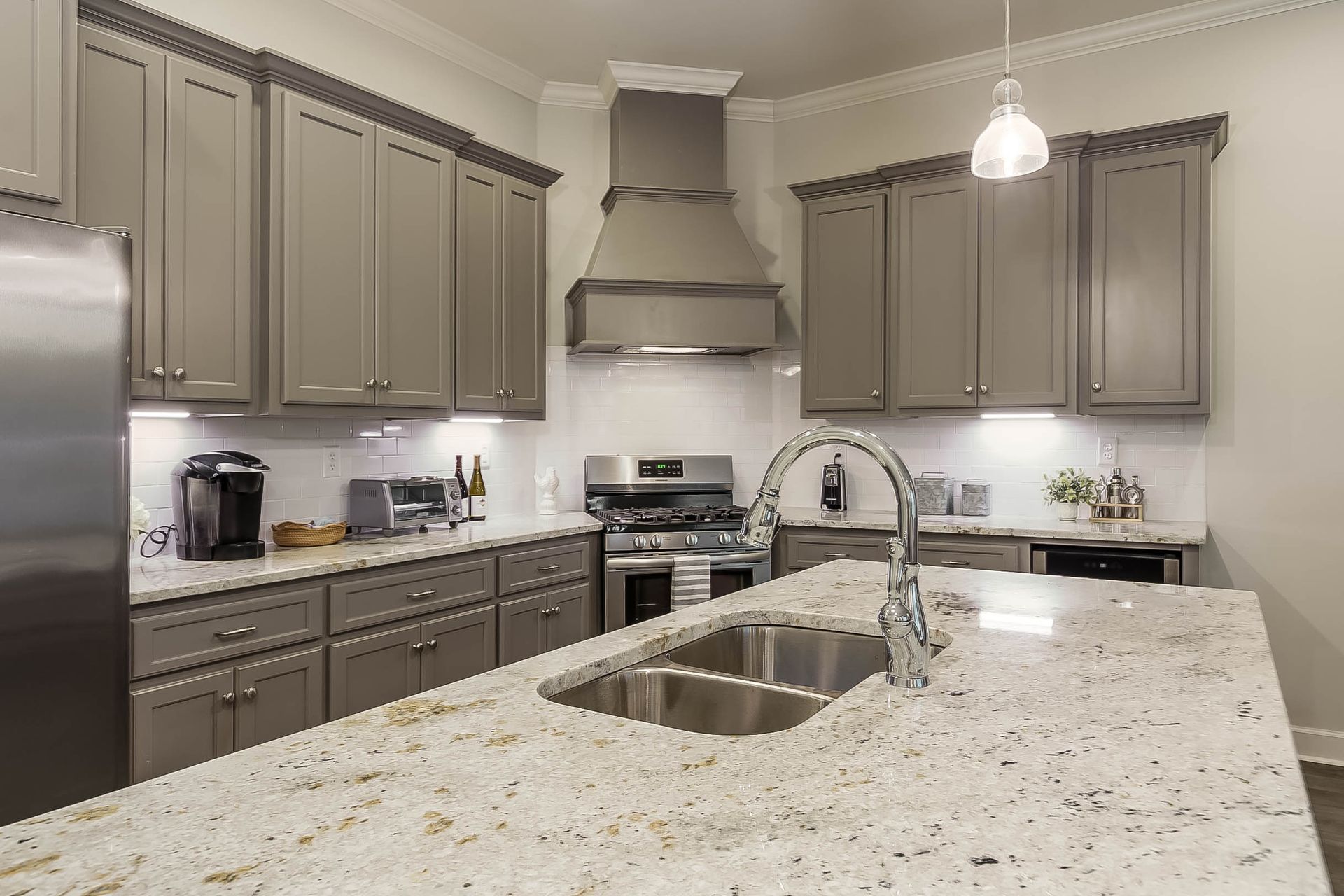 Gray kitchen with granite countertops, stainless steel appliances, and overhead cabinets.