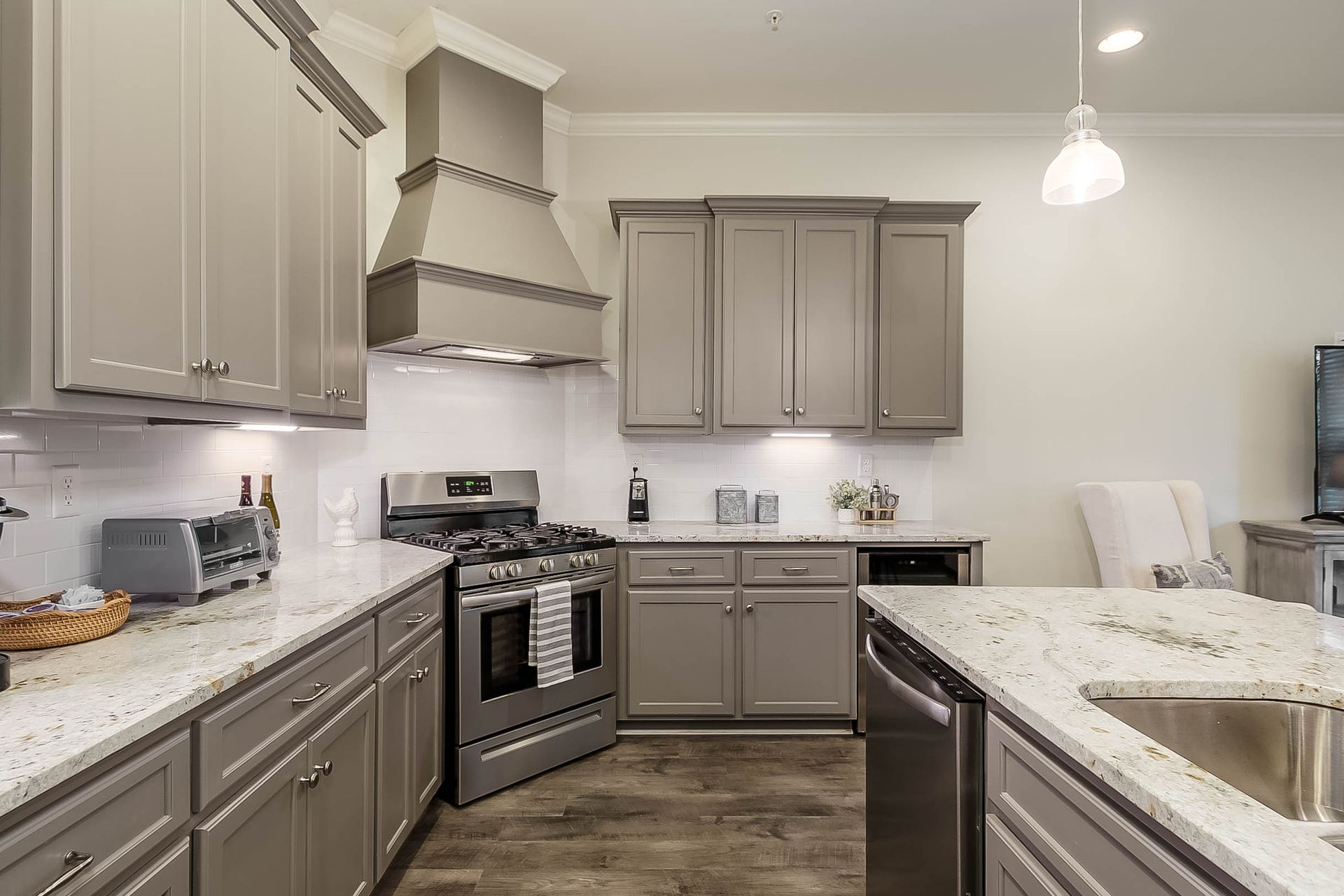Gray kitchen with stainless steel appliances, granite countertops, and light cabinets.