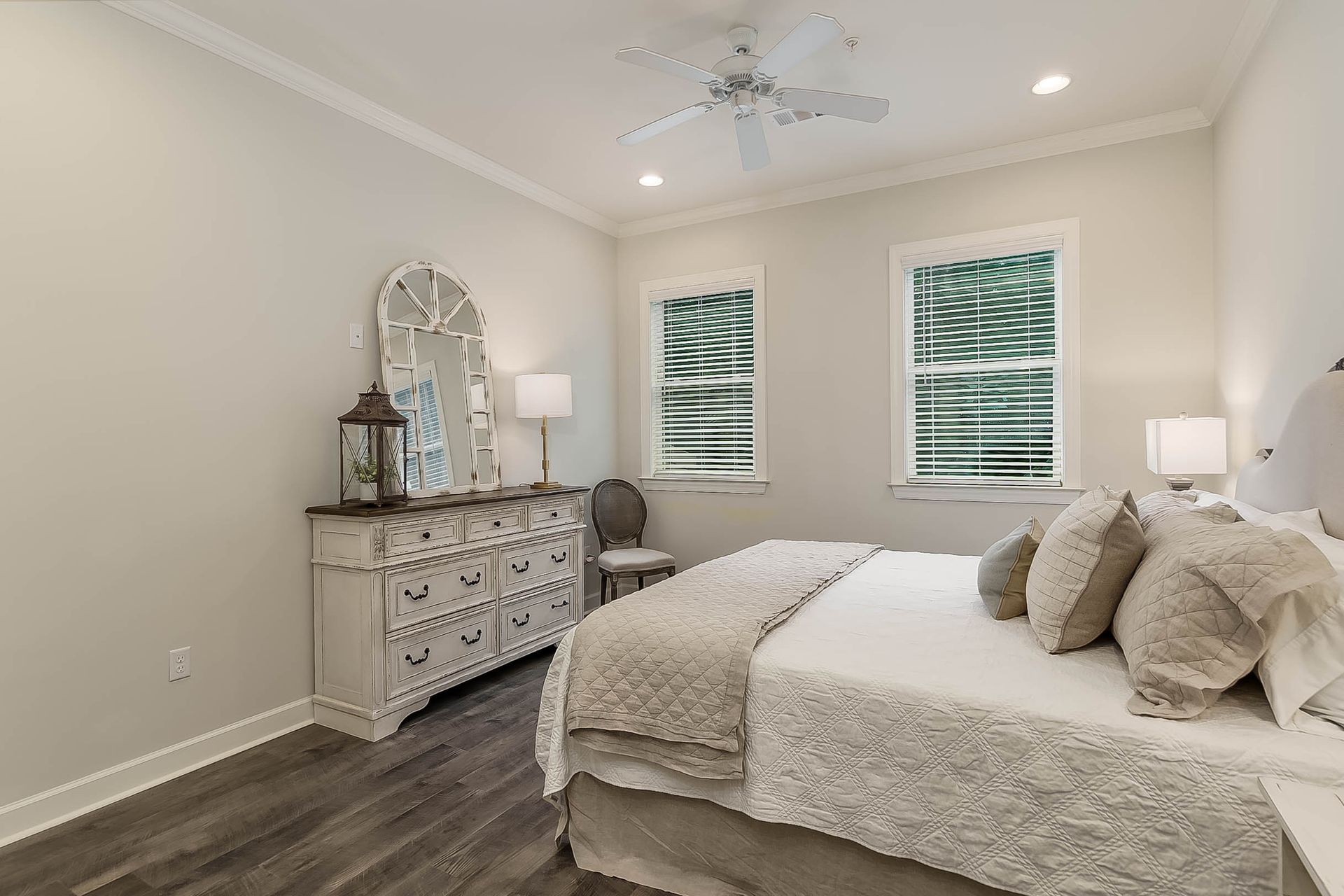 Bedroom with a white dresser, bed, windows with blinds, and a ceiling fan.