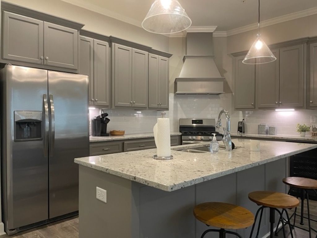 Gray kitchen with stainless steel appliances, granite countertops, and two pendant lights.