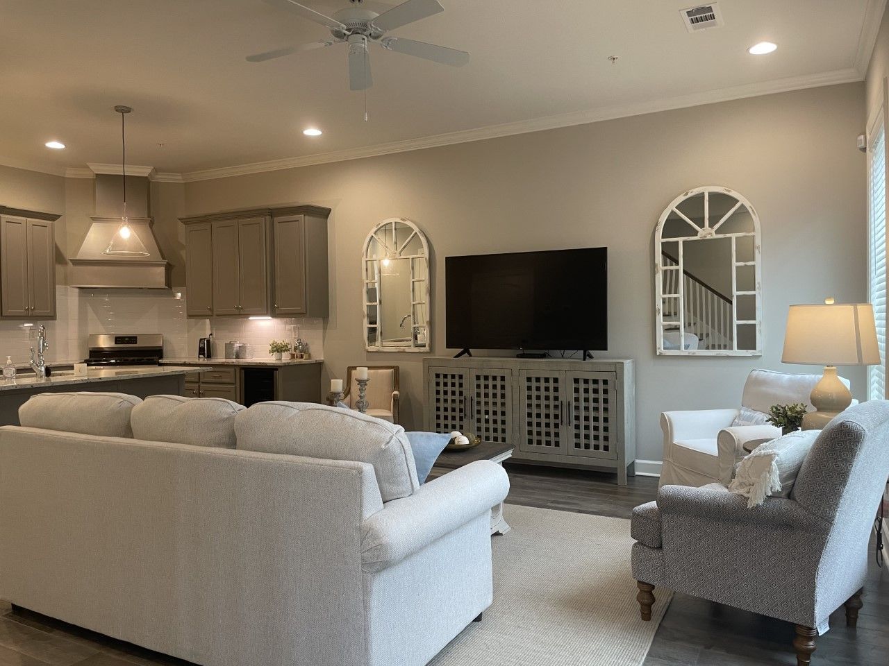 Living room with white sofa, gray cabinets, TV, and decorative mirrors.